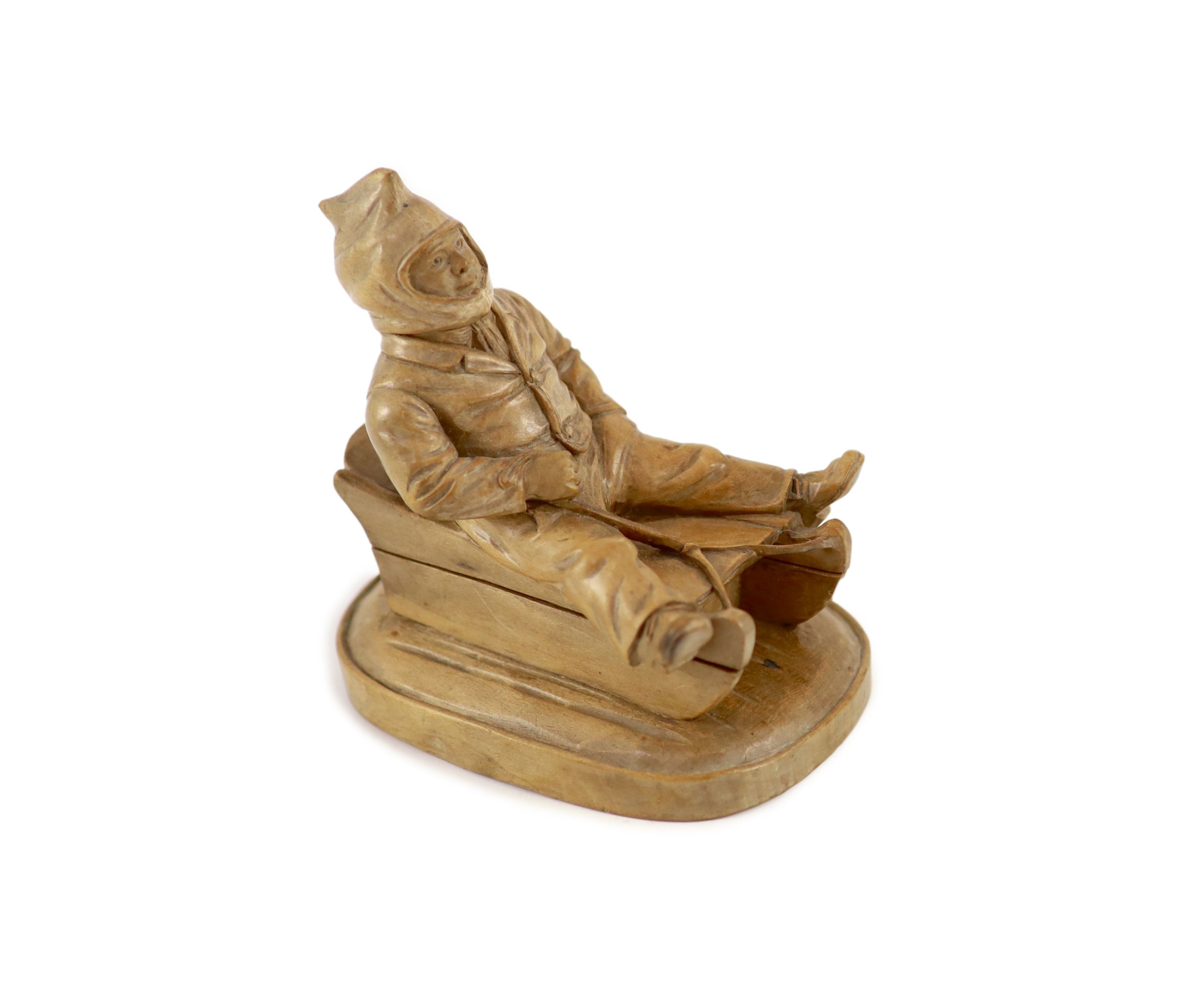 A North European novelty carved beech inkwell in the form of a seated figure sledging, c.1900, 11cm high, 11cm long.